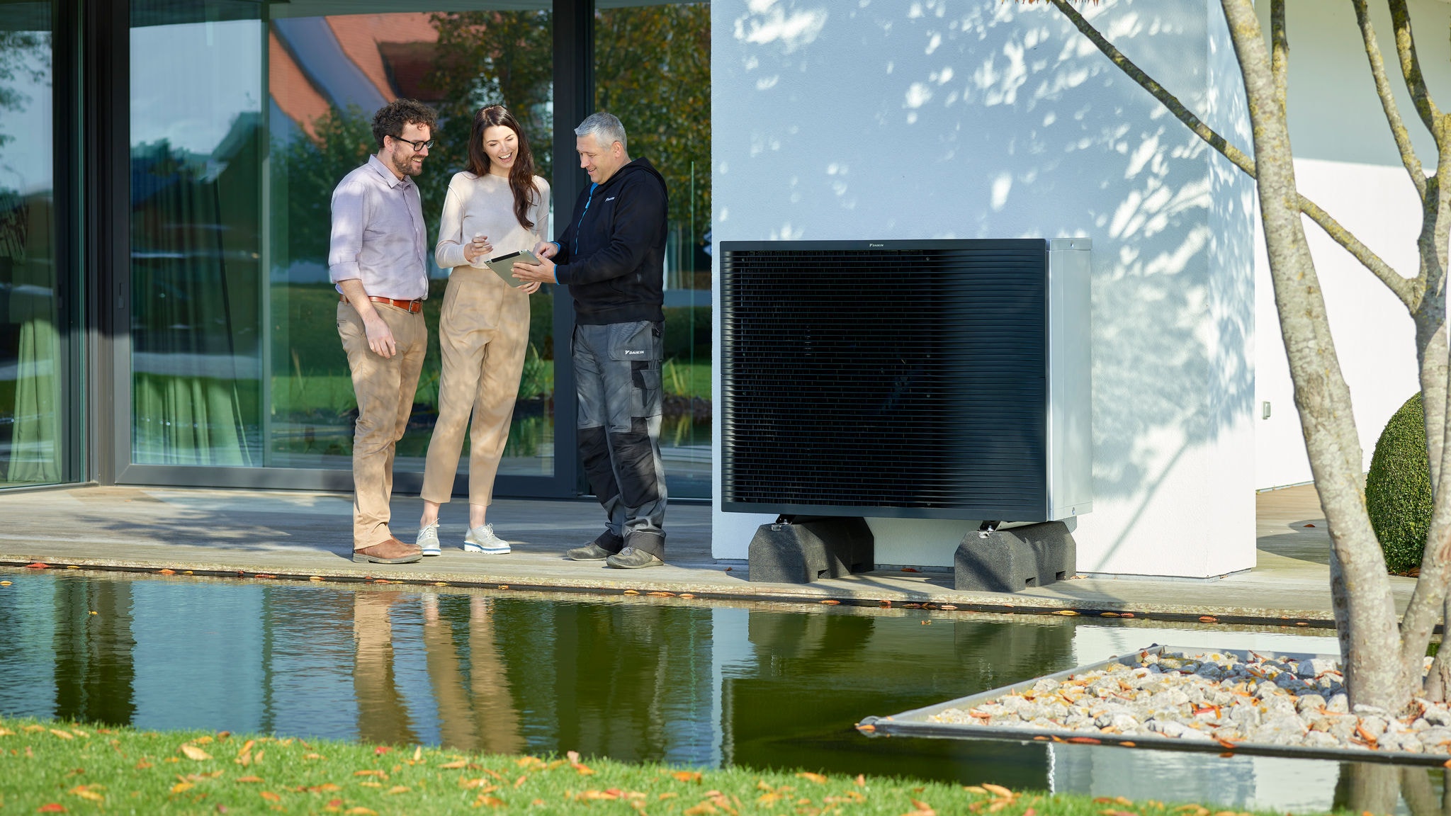 Casal a conversar com um instalador no jardim junto a uma unidade exterior Daikin Altherma